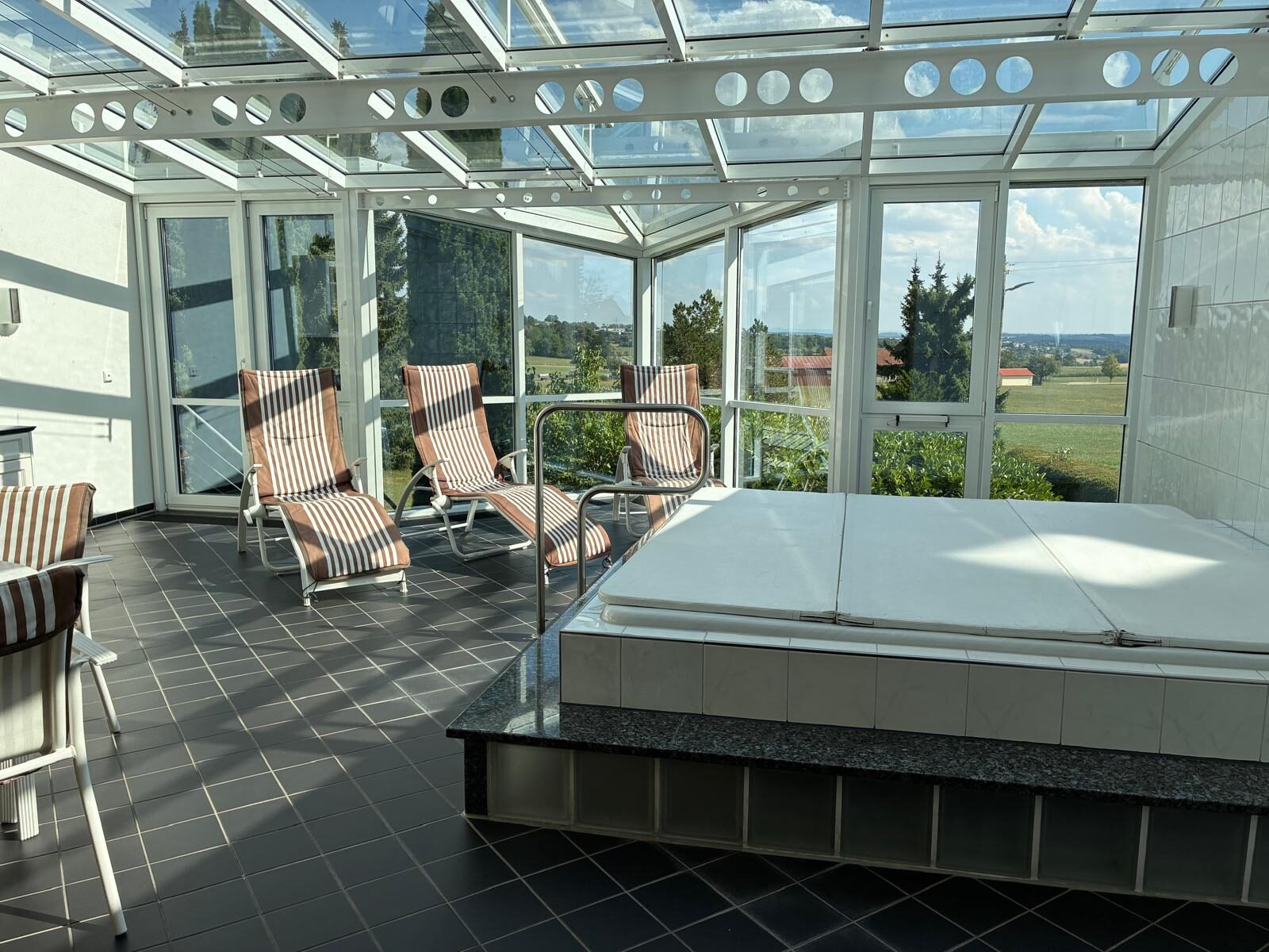 Whirlpool mit Relaxliegen unter dem Glasdach